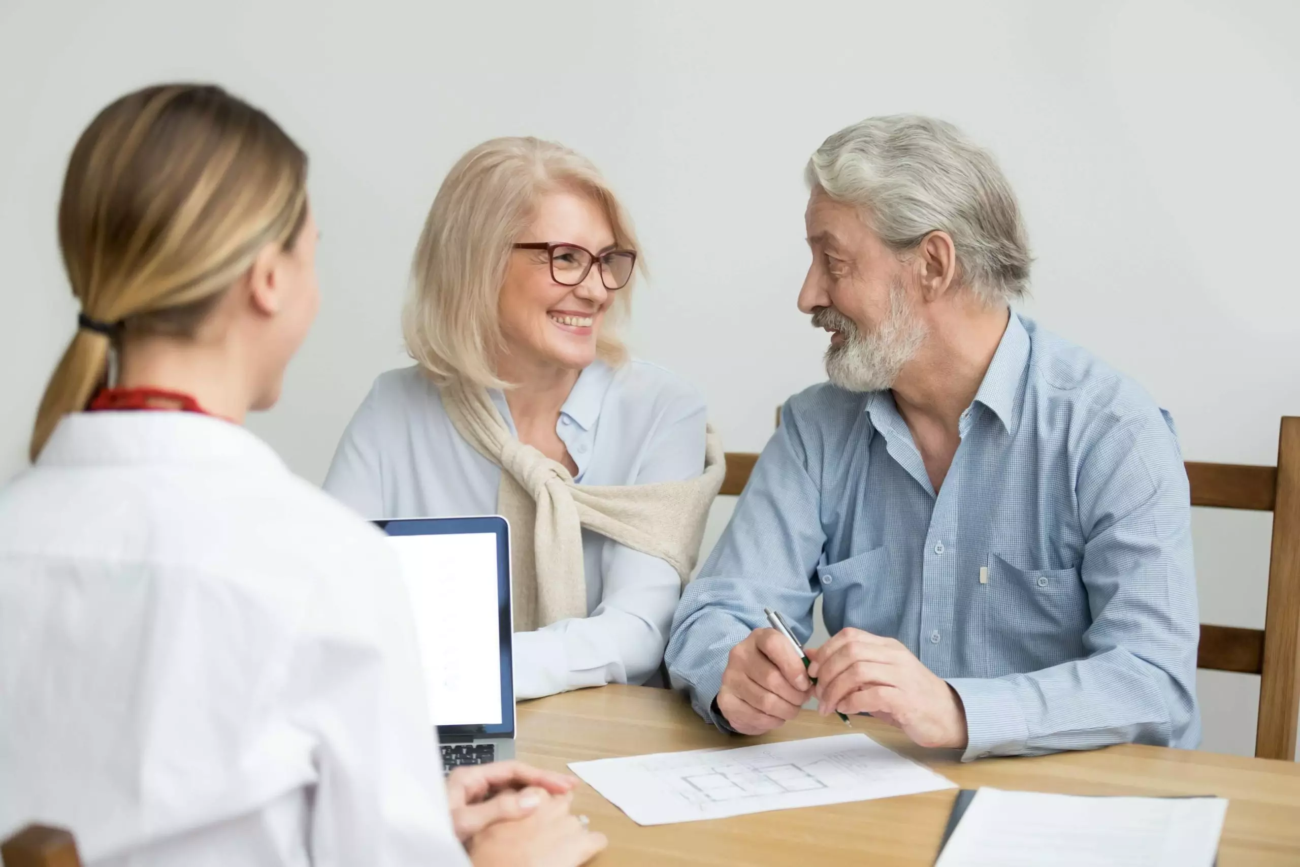 Happy senior couple deciding discussing new house purchase at meeting with agent